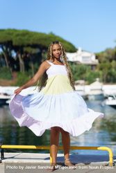 Female with braids in colorful summer dress standing on pier 0P7zvb