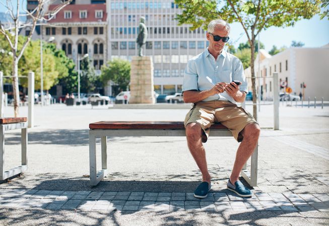 Male tourist sitting on bench outside in the city