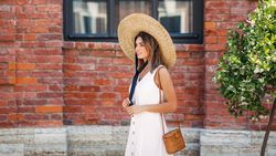 Woman walking next to brick building in summer time