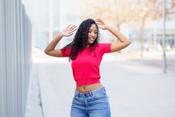 A Joyful Young Woman in a Stylish Outfit Posing Outdoors with Natural Scenic Beauty