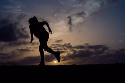 Jumping woman and sky with clouds at sunset