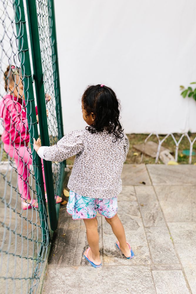 Two girls talking through metal fence