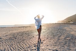 Woman walking along beach at dusk