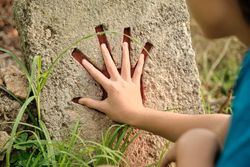 Unrecognizable child touching hand print on stone