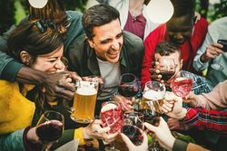 Group with many people celebrating a birthday toasting together with beers, wine and cocktails