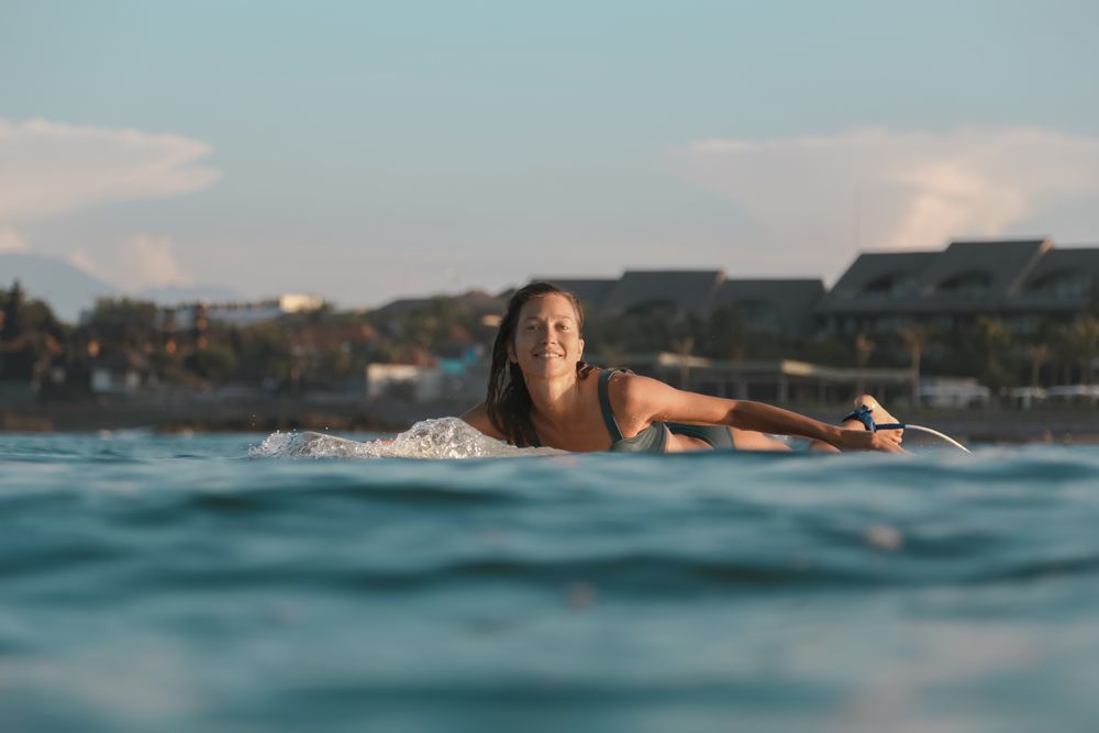 Smiling woman on surf board floating on water