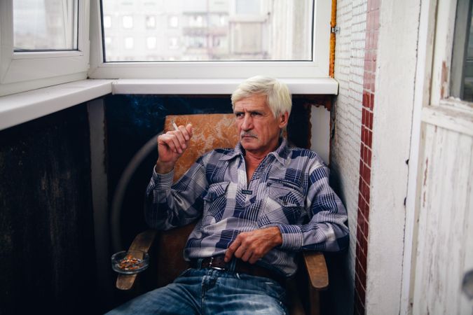 Older man sitting on chair smoking