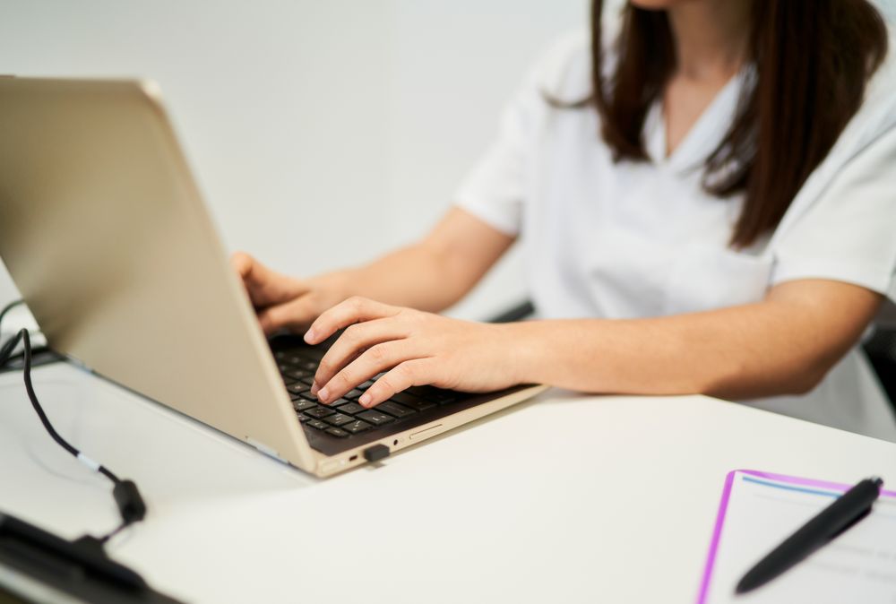 physiotherapist filling in the patient file on the laptop