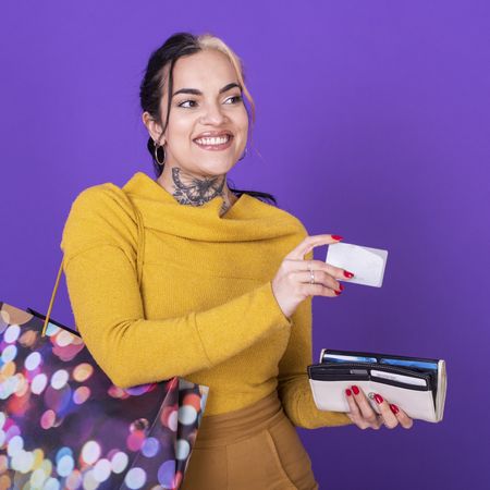 A women holding her wallet and shopping bag while showing a credit card.