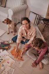 Kid and content mom painting near Spaniel dog at home