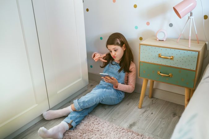 Girl with duck face taking selfie with the mobile for social media sitting on the floor