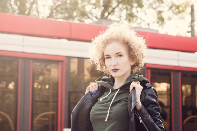 Curly woman walking outside next to bus