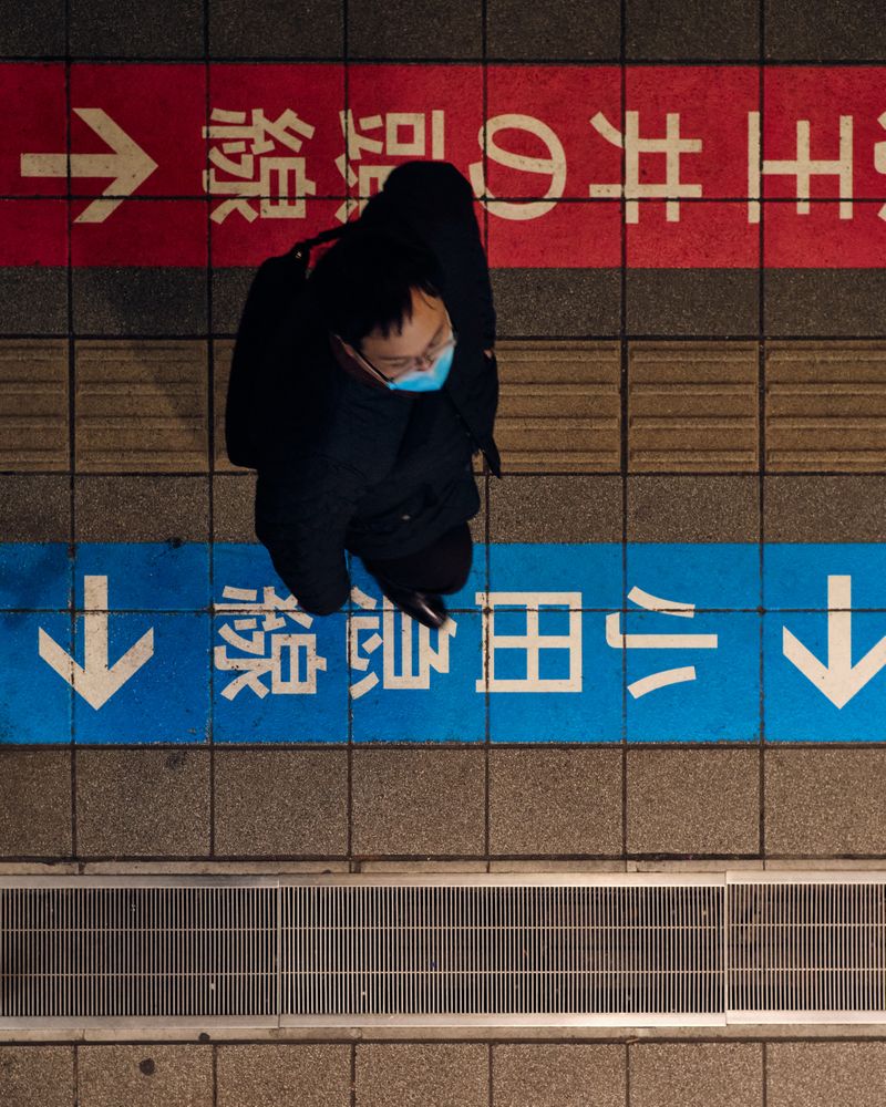 Top view of a man with facemask standing on sidewalk