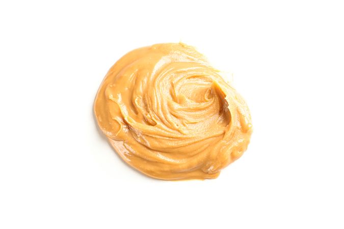 Creamy peanut butter isolated on light background. A traditional product of American cuisine