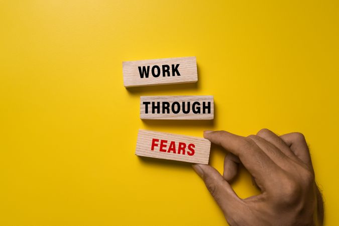 work through fears on wooden blocks isolated on yellow background