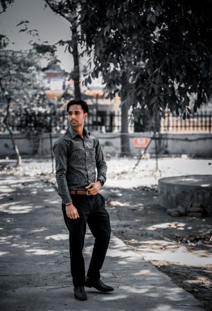 Man in gray dress shirt and dark pants standing outdoor