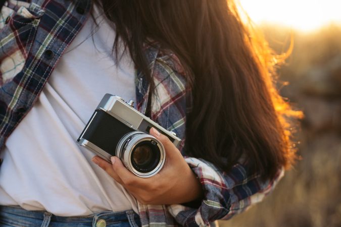 Unrecognizable woman taking photos with analog camera in the countryside