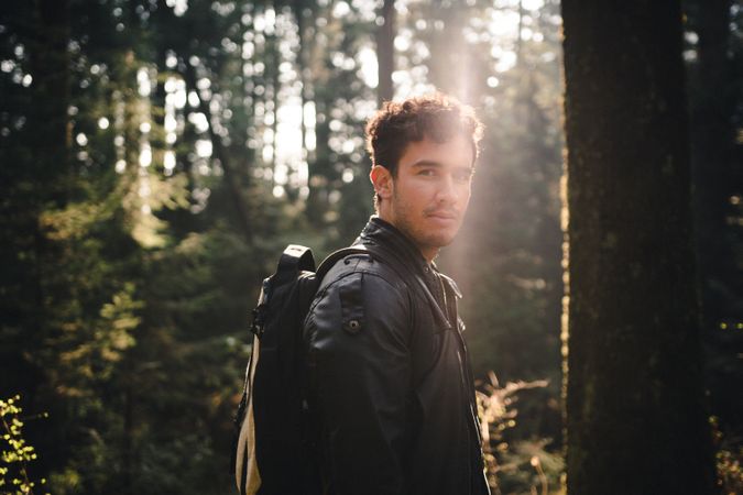 Man in dark leather jacket standing in forest