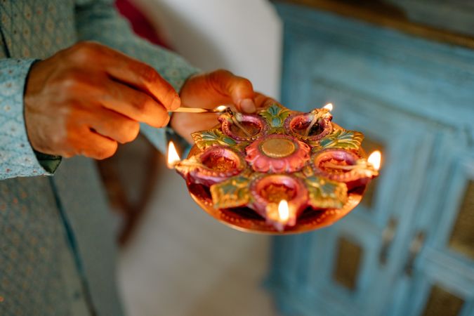 Cropped image of a person lighting up diyas during Diwali festival