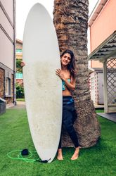 Female in wetsuit standing with her surfboard