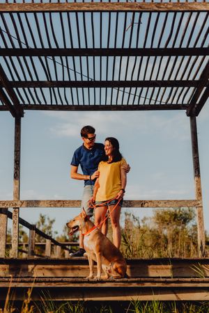Casual adult couple walking with dog at countryside