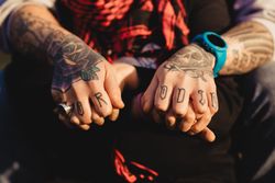 Man in tattoos holding hands of woman