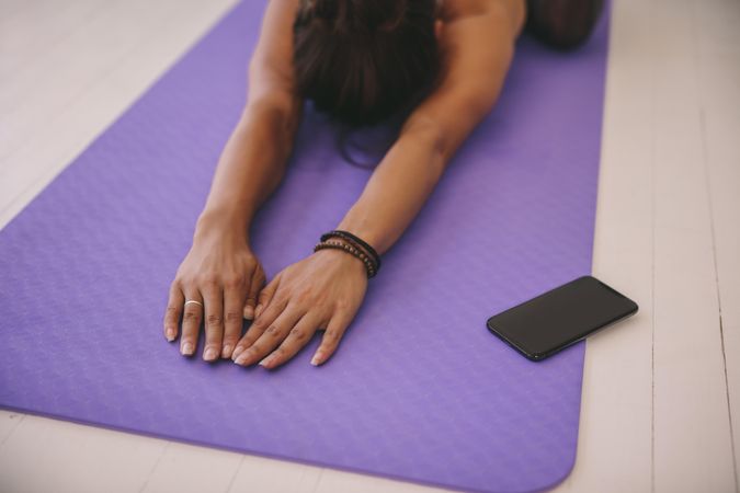Woman using phone app to do warm up stretching on mat