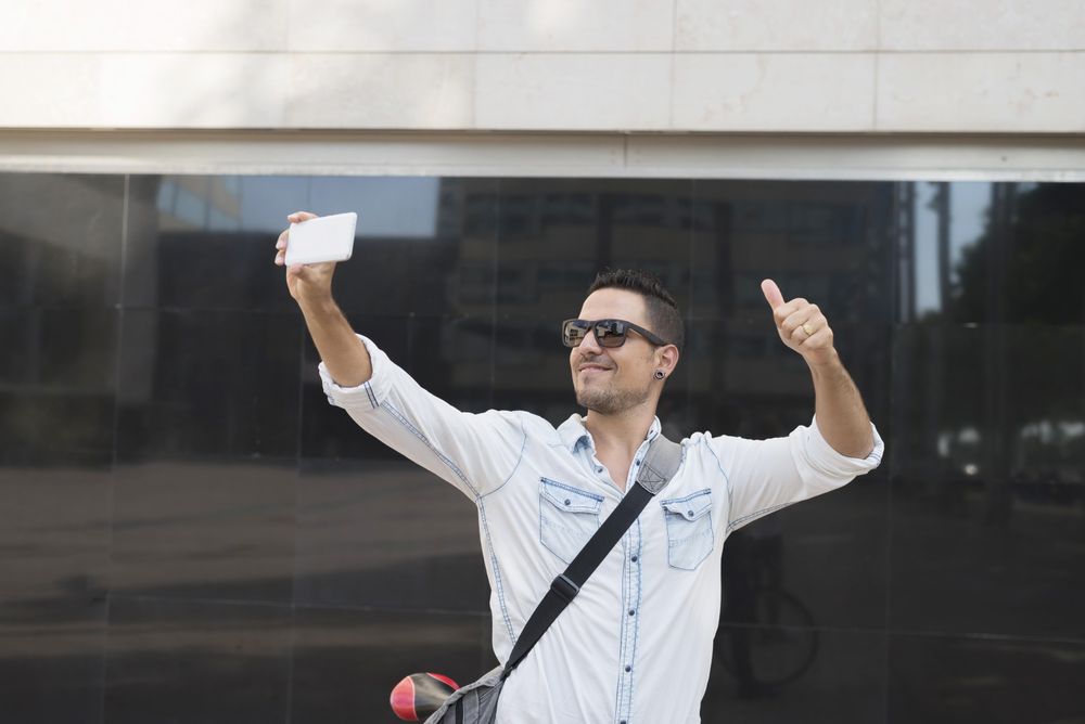 Male making thumbsup sign and taking selfie
