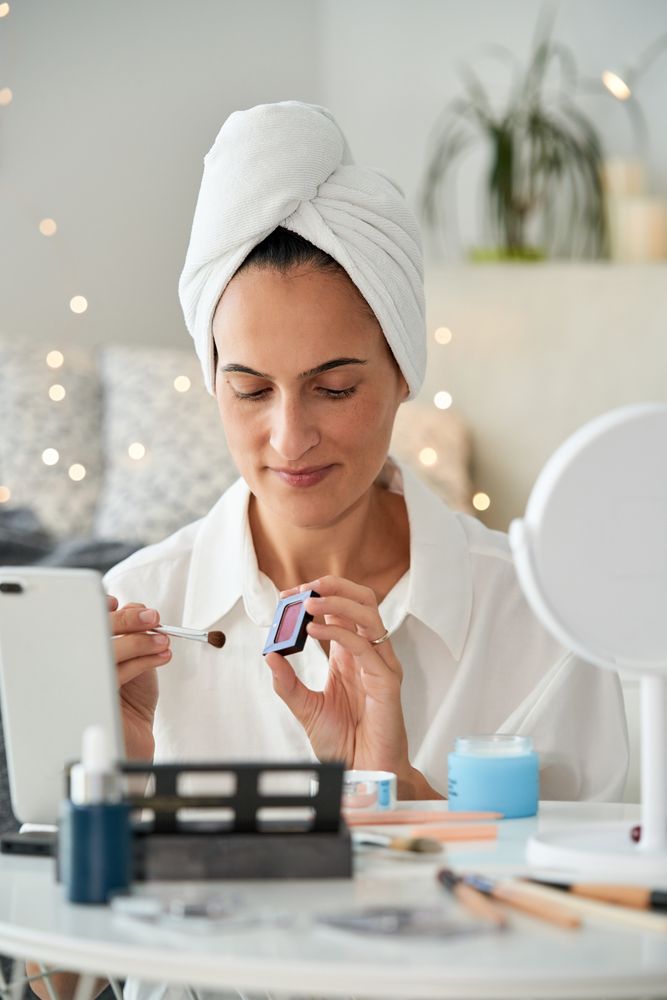 Content woman showing eyeshadow on smartphone camera