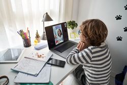 Boy having video call with friend and looking at screen of lapto