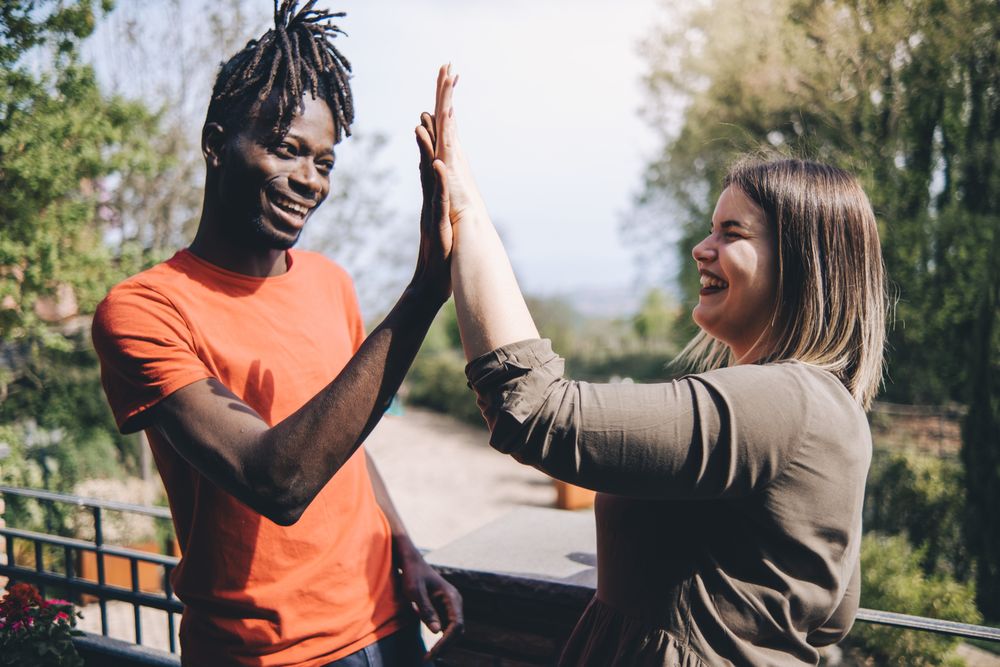 Interracial couple high-fiving outside