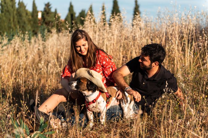 Happy couple with friendly cute dog resting outdoors