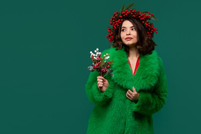 Woman in green coat and red berry wreath