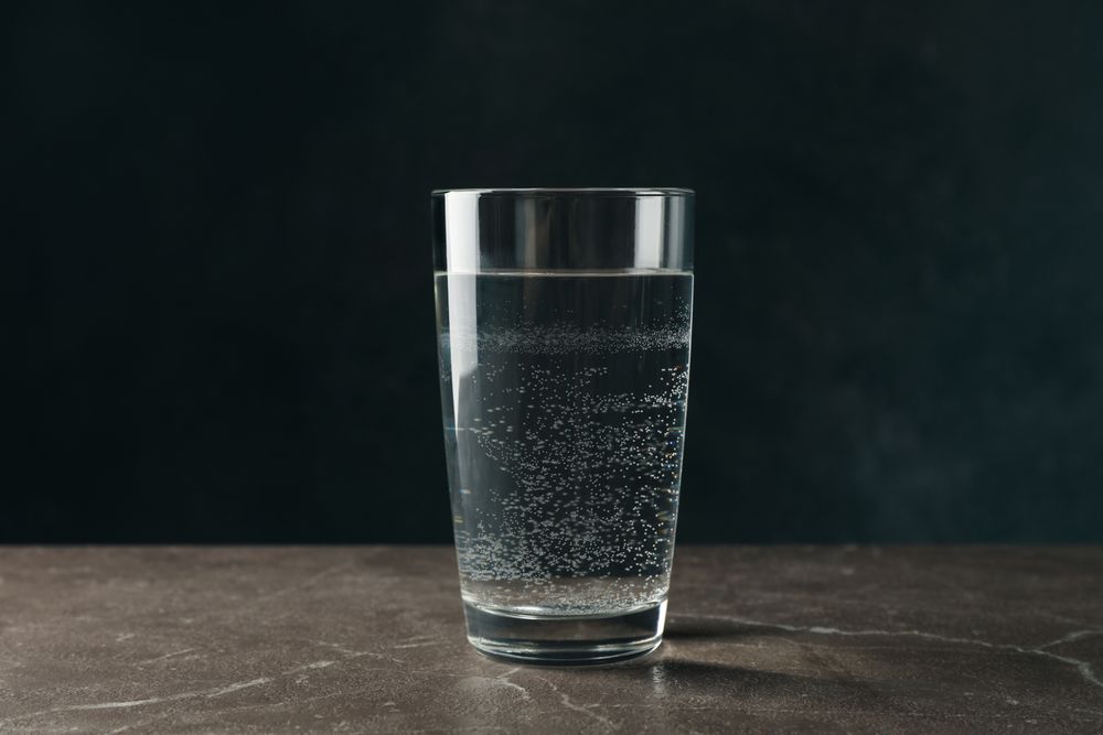 Single glass of water in dark room on marble table