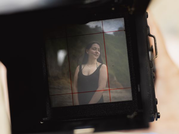 A young woman is photographed with an antique camera, during a relaxing day on a natural beach