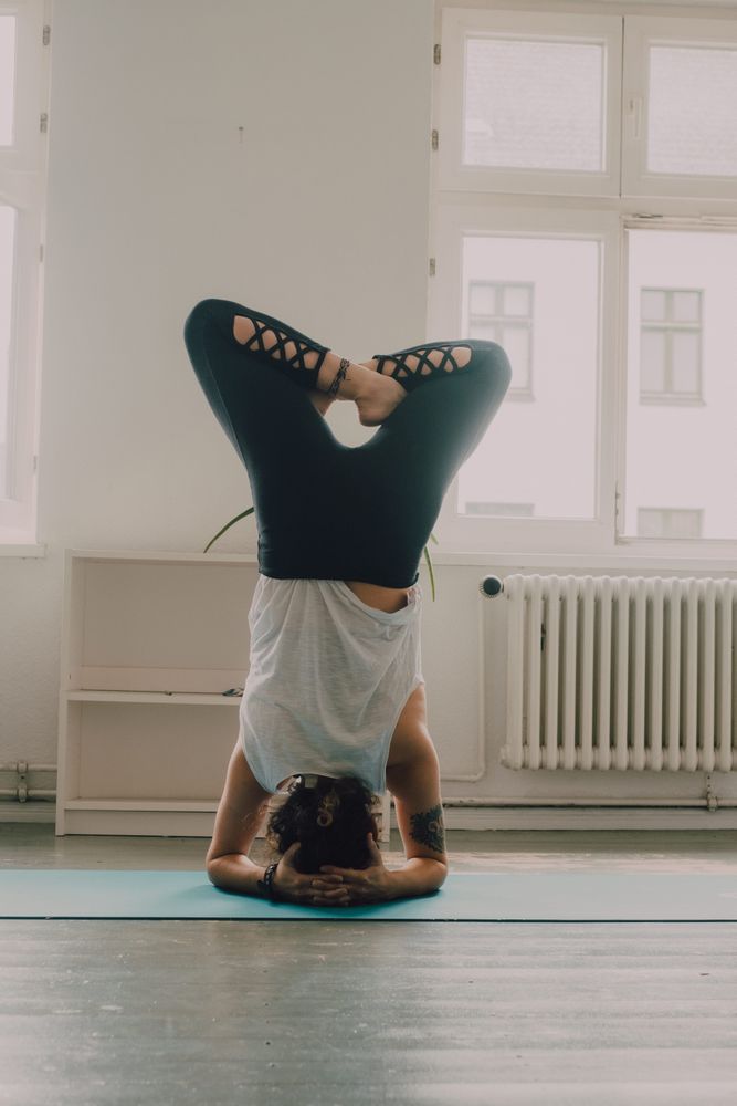 Fit woman practicing yoga pose and standing on head at home