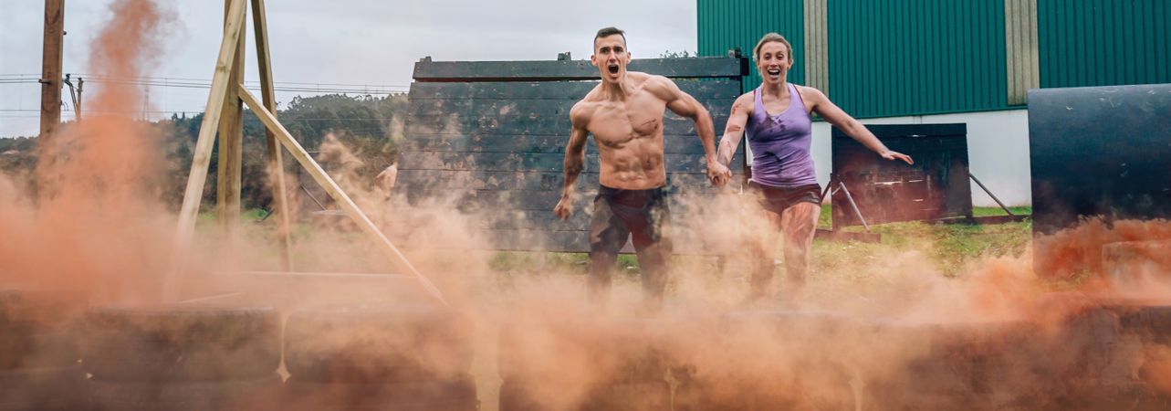 Athletes jumping finish line of an obstacle course