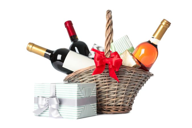 Wicker basket with bottles of wine and presents isolated on light background