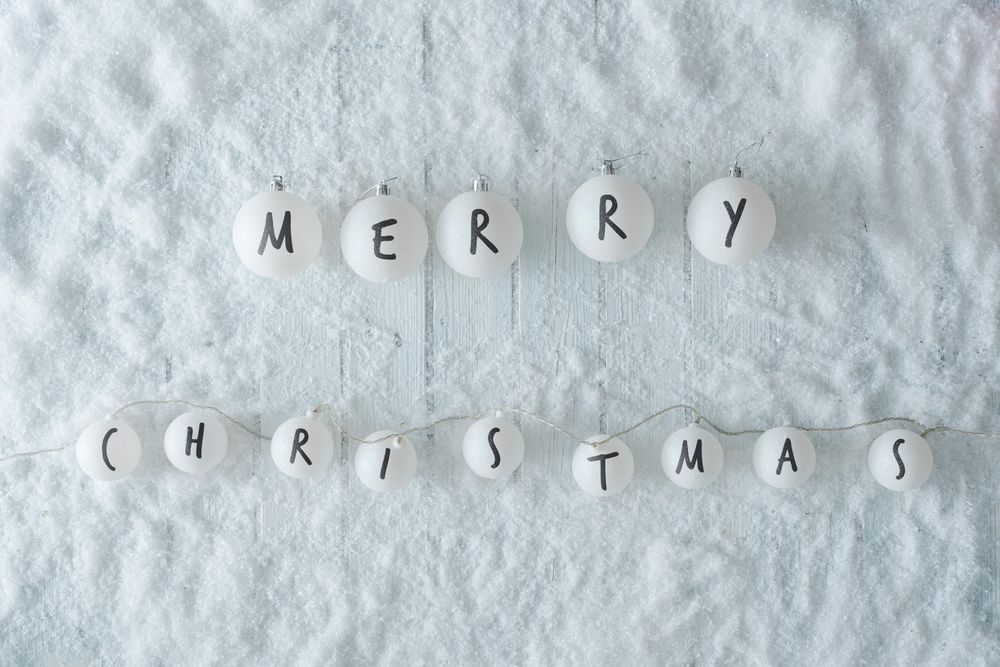 Wooden table background with snow and lights ball decoration reading “Merry Christmas”