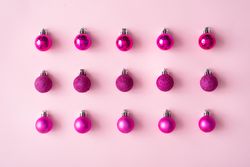 Arrangement of pink festive baubles in rows on pink background