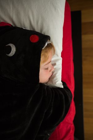 Boy in unicorn pajama sleeping in bed