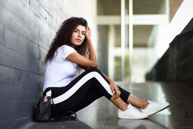 Contemplative female in leggings sitting outside of building entrance