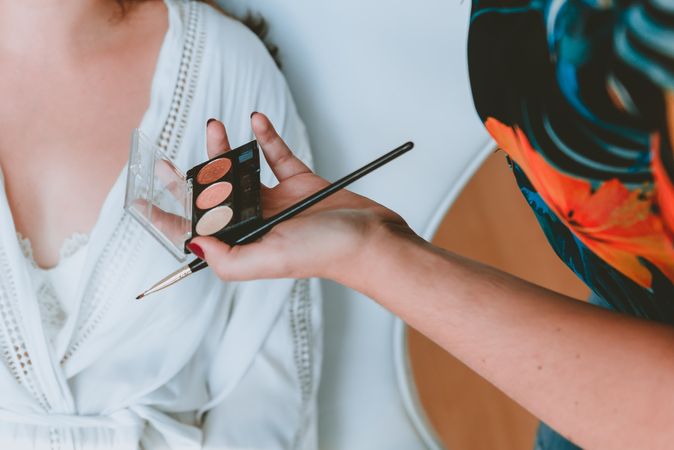 Woman hand with brush and powder near lady