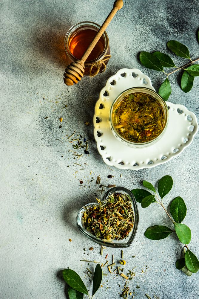 Top view of floral tea in glass with honey pot and dipper with copy space
