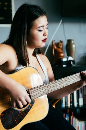 Close up of woman playing guitar inside house