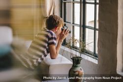 Boy on sofa looking outside window using binoculars 5o929b