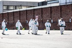 People in PPE holding sanitizing machine outdoor