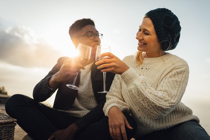 Lovely couple toasting wine while sitting outdoor on sunny day