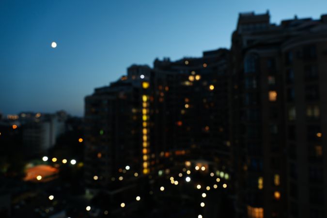 Beautiful city sunset with multi-storey building against clear sky with moon