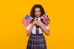Smiling girl holding both USA and UK flags